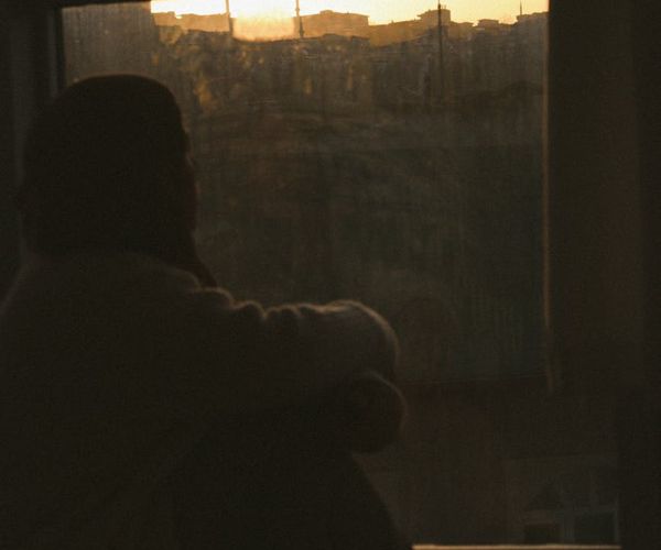 Person meditating peacefully near a window with soft light.