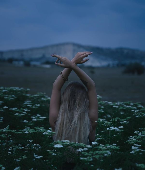 Woman performing a gentle yoga pose in a calm, dark environment.